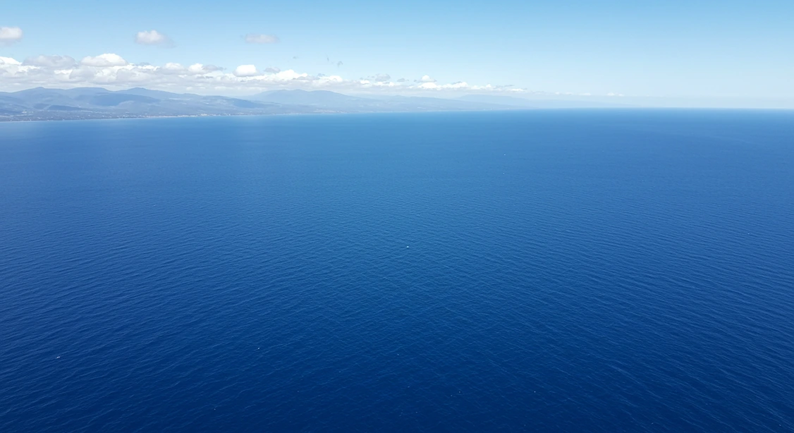 Vista aérea do imenso Oceano Pacífico sob um céu claro e azul, transmitindo a grandiosidade e a beleza natural do maior oceano do mundo.